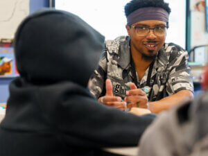 A teacher working one-on-one with a student at the student's desk.