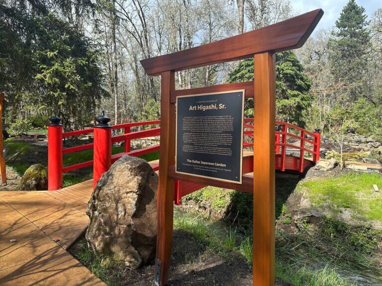 A torii gate with signage about garden designer Art Higashi.