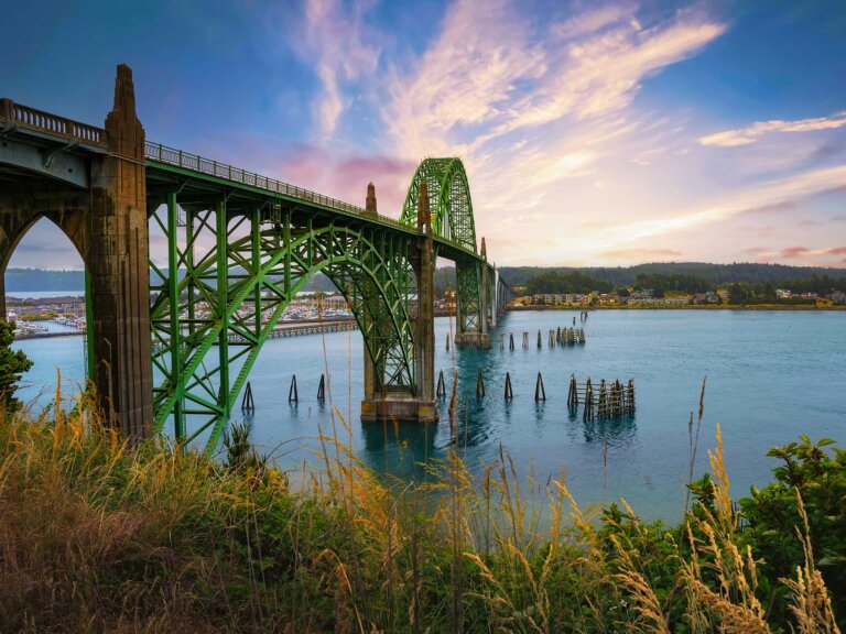 Yaquina Bay Bridge against a blue sky with sparse white clouds