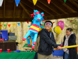 A blindfolded boy swings at a pinata during a celebration.