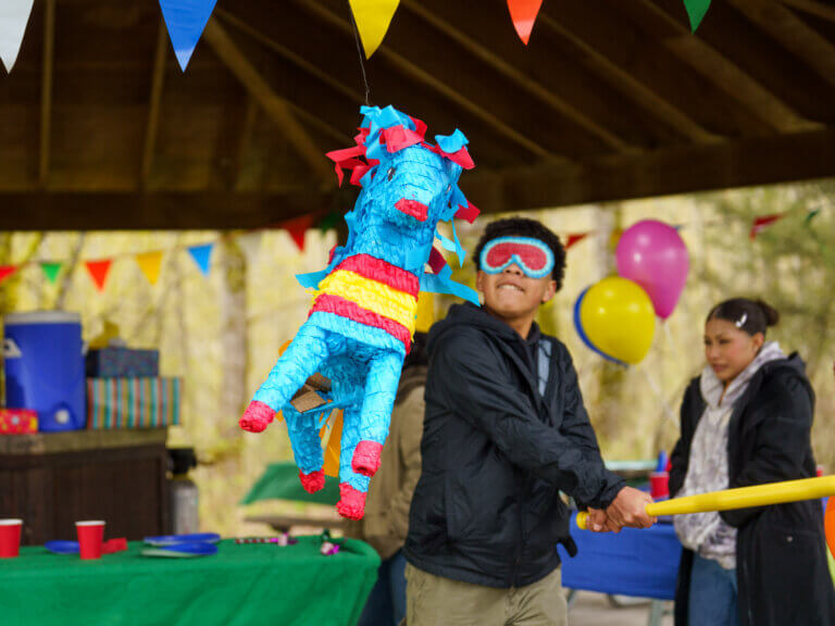 A blindfolded boy swings at a pinata during a celebration.